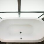 a white bath tub sitting next to a green plant