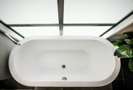 a white bath tub sitting next to a green plant