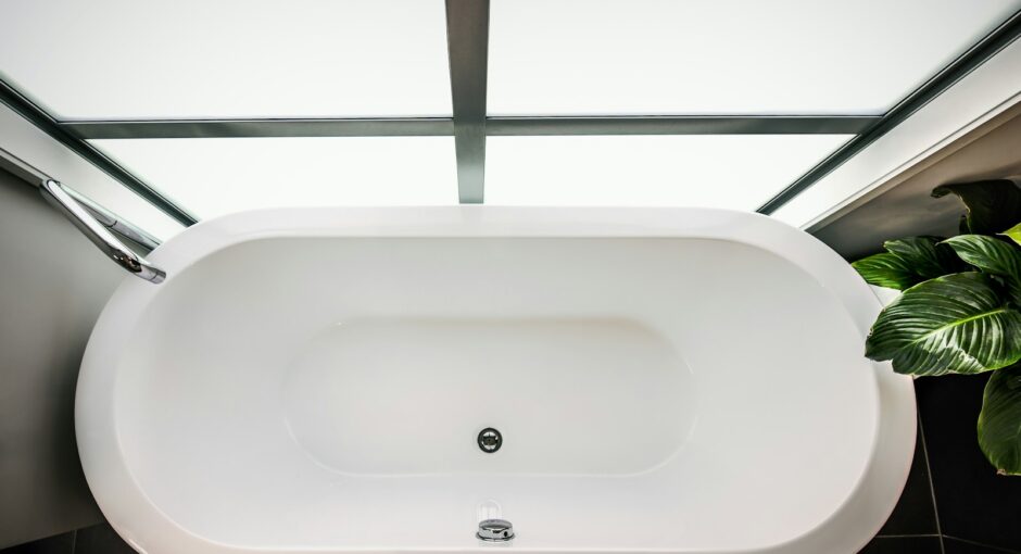 a white bath tub sitting next to a green plant